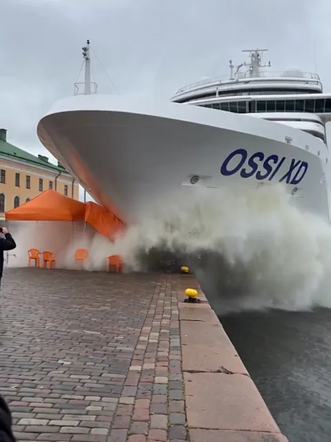 Valkoinen megajahti on noussut keulallaan Kauppatorin laiturille, ja aalto huuhtoo torikojuja.